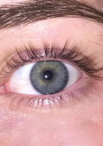 Close-up van een groen oog met lange natuurlijke wimpers en verzorgde wenkbrauw.