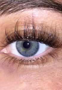 Close-up van een blauw oog met lange, volle wimpers en natuurlijke wenkbrauw.