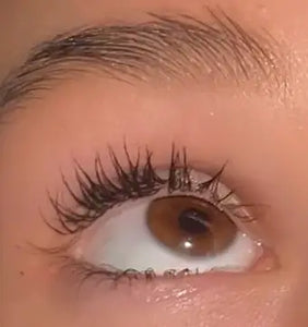 Close-up van een bruin oog met volle, gekrulde wimpers en verzorgde wenkbrauw