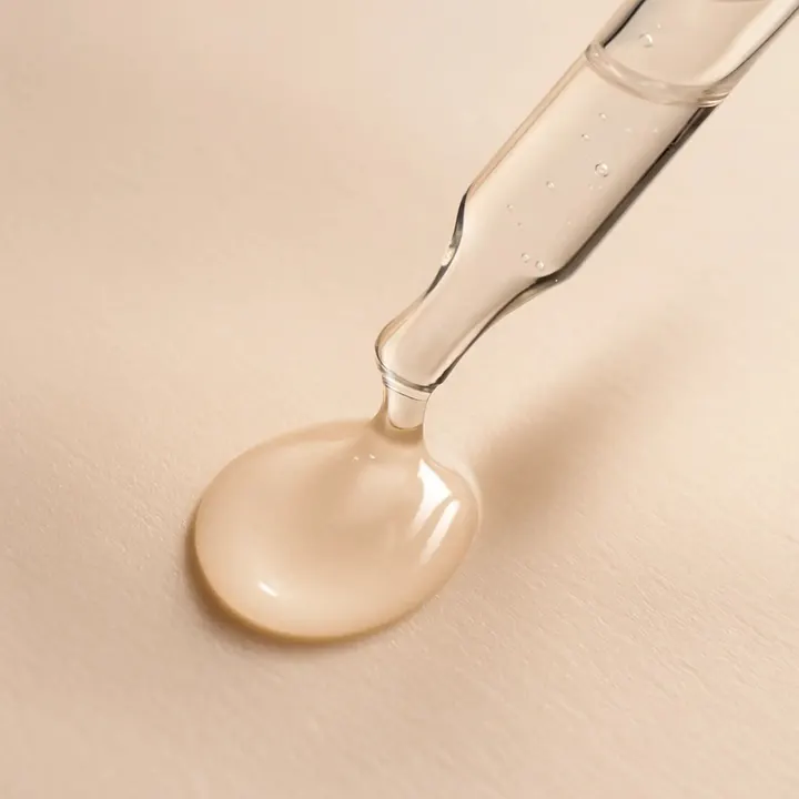 Close-up van pipet met transparant gezicht serum op een licht beige achtergrond